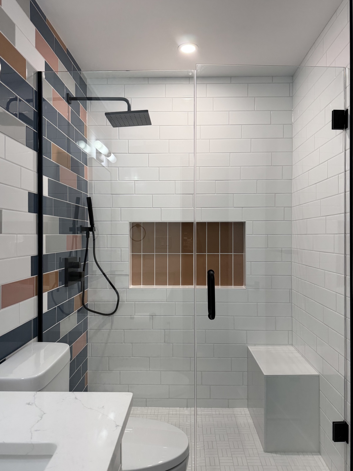 Renovated bathroom with glass walk-in shower and multicolour tile feature wall
